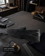 New Balance 1906L U1906LBN 全黑樂福鞋內側，置於皮革與西裝布料工坊桌面