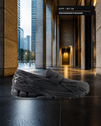 New Balance 1906L U1906LBN 全黑樂福鞋側面，置於晨間都會辦公騎樓的玄武岩地面
