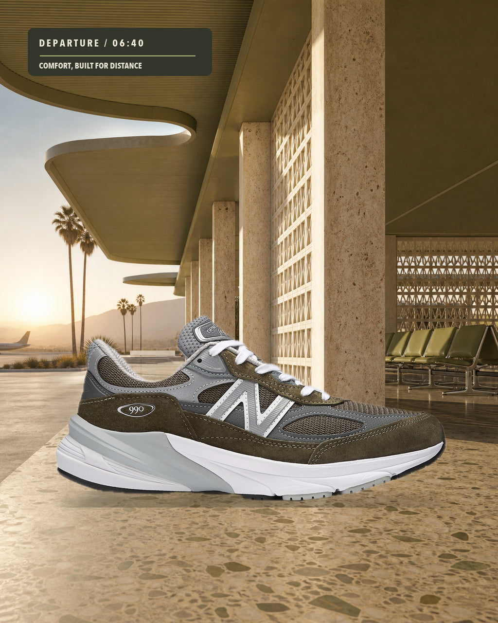 New Balance 990v6 U990OG6 灰橄欖綠跑鞋側面，置於沙漠機場航廈的乾燥磨石地面